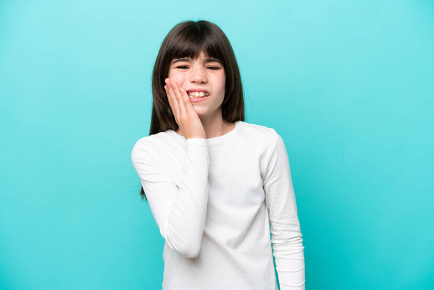 Little caucasian girl isolated on blue background with toothache - 写真・画像