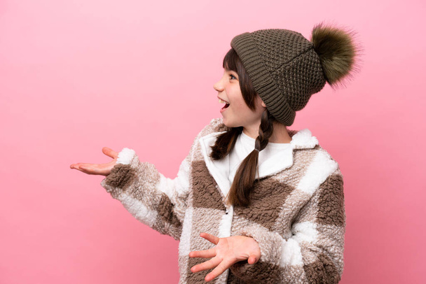 Little caucasian girl with winter jacket isolated on pink background with surprise facial expression - Фото, изображение