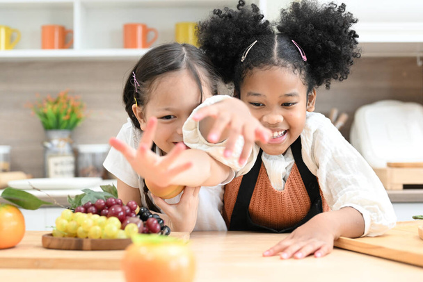 Crianças felizes meninas com pão e biscoitos brincando com farinha e rir na cozinha, meninas fazendo pão na cozinha, crianças de pé no balcão de culinária preparando o ingrediente para a refeição do jantar - Foto, Imagem