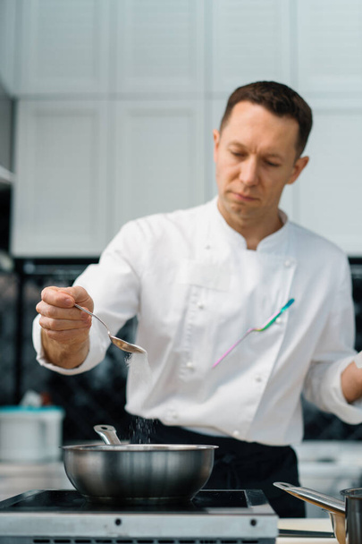 професійний кухонний шеф-кухар додає цукор до гарячого вівсяного горщика, готуючи сніданок здорової концепції харчування
 - Фото, зображення