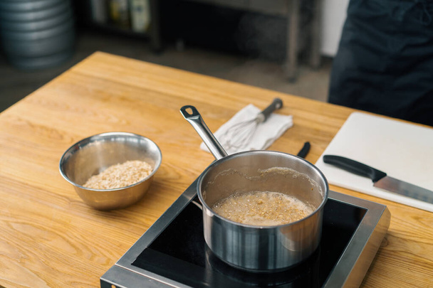 健康的な朝食キャセロールステンレス製のラドルストーブの上で沸騰したオートミールとお粥の完全な料理のコンセプト - 写真・画像