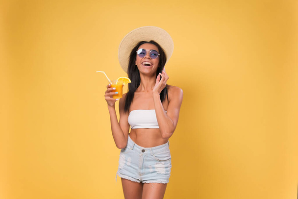 happy African American woman drinking a cocktail having fun. Summer beach holiday concept. isolated over yellow background - Zdjęcie, obraz