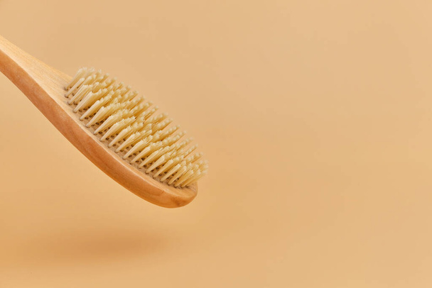 Wooden brush for anti-cellulite dry body massage, scrub made of eco friendly bamboo fiber. Body care at home. Beige background, copy space - Photo, Image