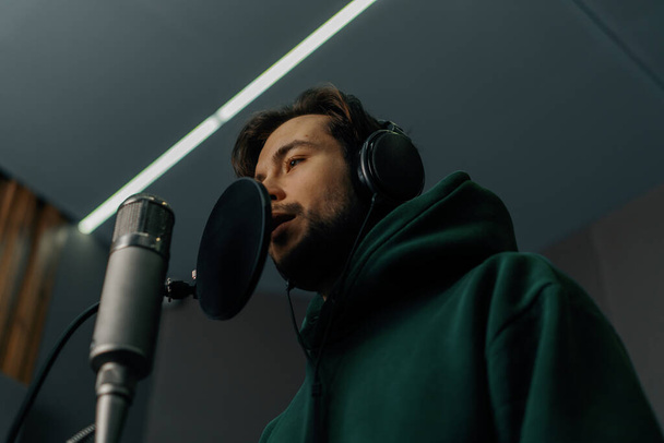 singer with headphones and microphone emotionally recording a new song in professional recording studio - Φωτογραφία, εικόνα