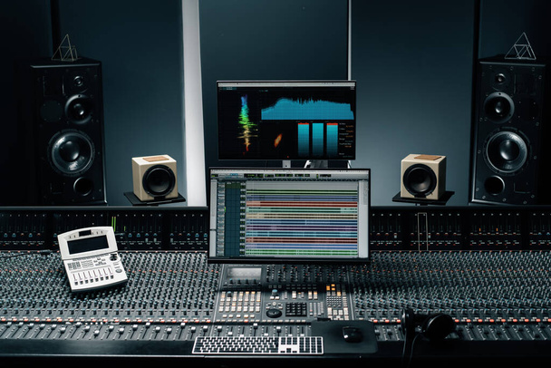 estúdio de gravação com uma tela com configurações de onda sonora e volume dois subwoofers e console de mistura - Foto, Imagem