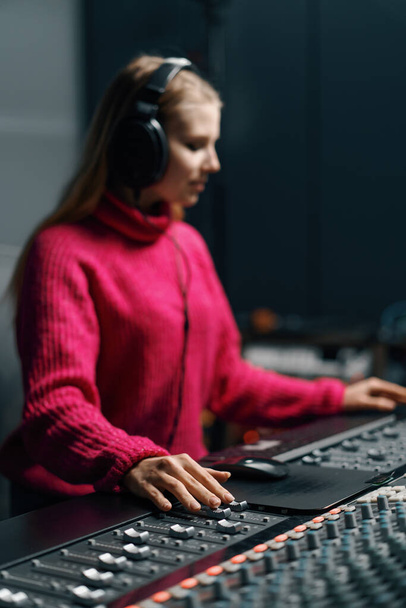 krásný mladý zvukař ve světlém oblečení používá digitální audio mixér stiskne klávesu ovládací panel - Fotografie, Obrázek