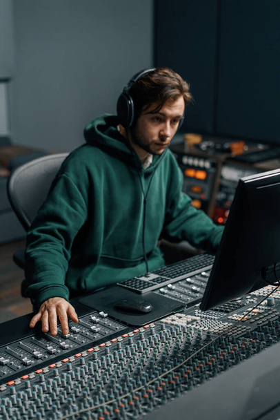 Звукоинженер, работающий в домашней музыкальной студии с мониторами и эквалайзером - Фото, изображение