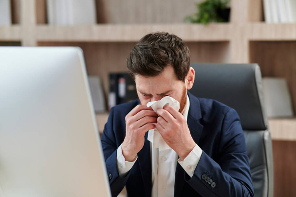 Business workers at his office desk sneezes and feels bad. Sickness, virus, flue - Foto, Imagen