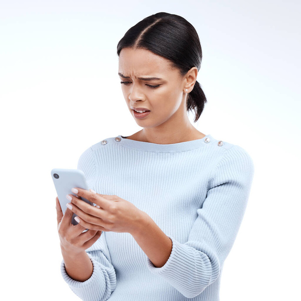 Confused, woman and phone in a studio reading a phishing, scam and fake news text. Isolated, white background and mobile texting of a young and gen z female with online and spam email with wtf. - Fotoğraf, Görsel