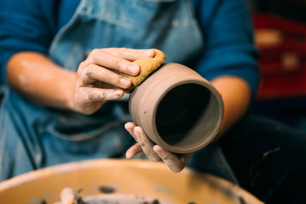 Профессиональный гончар, делающий кувшин из глины на круге гончарных кругов в мастерской, традиционная ремесленная работа, творчество и искусство керамики, ремесленник, работающий с мокрой глиной, декорируя и формируя - Фото, изображение