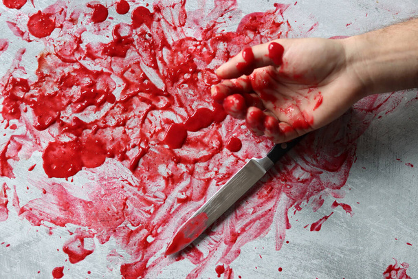 Ręczny nóż na krwawym brudnym tle z przestrzenią do kopiowania. Morderstwo z premedytacją. Krwawa dłoń trzymająca nóż z krwią.  - Zdjęcie, obraz