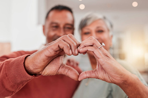 Coppia, anziani e cuore in casa, amore e legame in pensione insieme. Romanticismo, gesto della mano e anziani con emoji per la cura, l'affetto e l'empatia, l'impegno e la fiducia - Foto, immagini