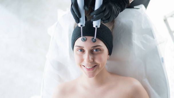 Young caucasian woman on microcurrent therapy procedure. Beauticians office - Foto, Bild