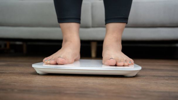 Fat diet and scale feet standing on electronic scales for weight control. Measurement instrument in kilogram for a diet control - Photo, Image