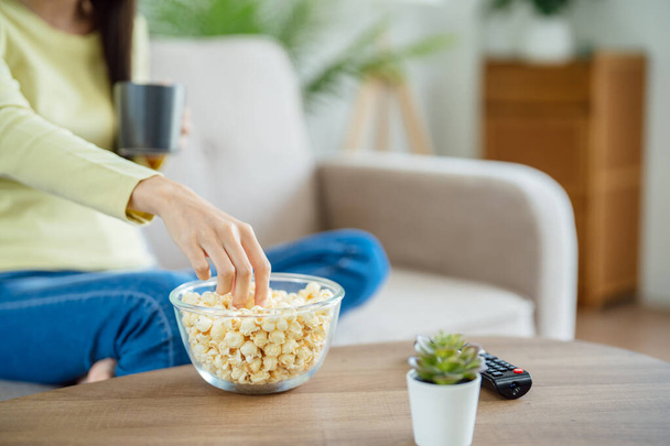 Asian woman Watching smart TV and using remote controller Hand holding television audio remote control at home with popcorn - Photo, image