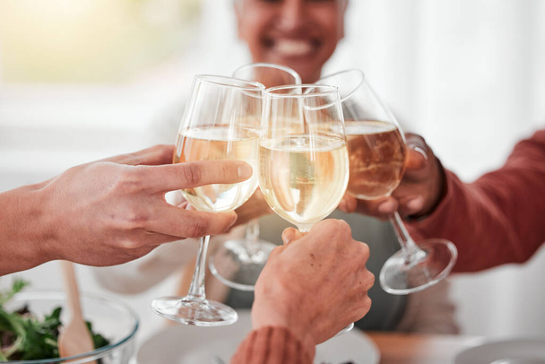 People, hands and cheers for happy dinner, fine dining or celebration for meal or friendship together. Hand of family or friends toasting by table for food, drink or bonding in celebration at home. - Foto, afbeelding