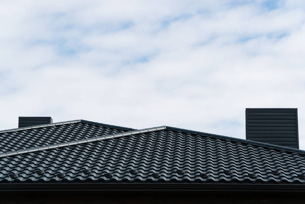 Het dak is gemaakt van zwarte metalen tegels. - Foto, afbeelding