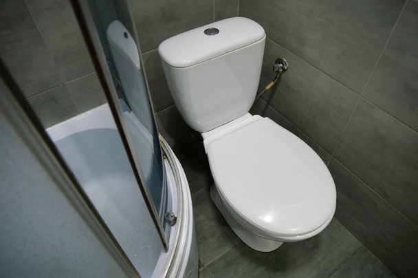 白いトイレボウル、シャワーキャビン、グレーの壁のタイルとトイレの部屋のインテリア - 写真・画像