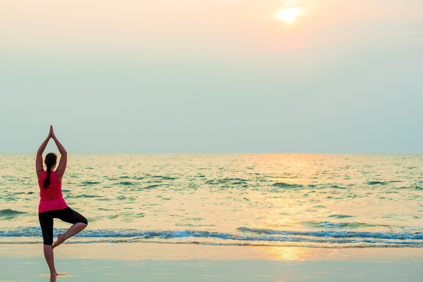 стройная девушка балансирует на одной ноге. Йога на пляже
 - Фото, изображение