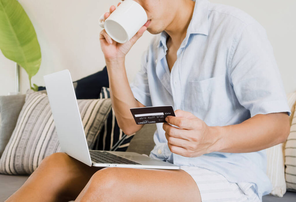 человек с помощью кредитной карты Вход в ноутбук, пить кофе и расслабиться, личные финансы и финансовые технологии концепции. - Фото, изображение