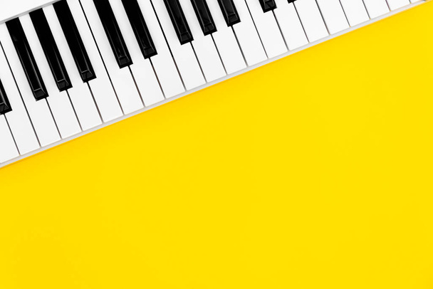 黄色の背景のピアノキー、トップビュー、フラットレイアウト、コピースペース. - 写真・画像
