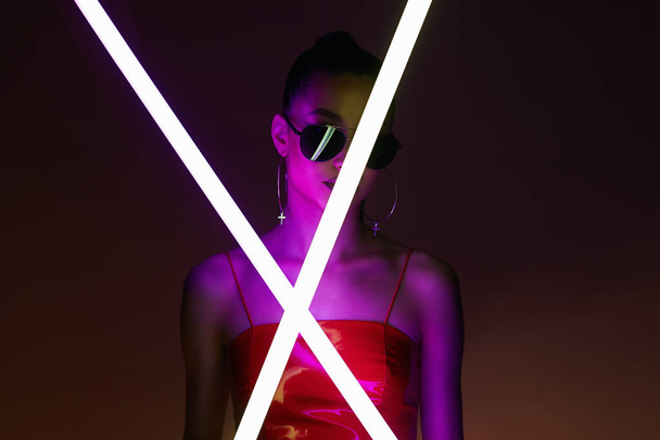 beautiful young woman with neon lamp. Pretty girl in sunglasses in color lights. - Foto, Imagen