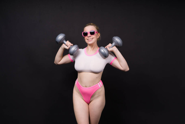 Seductive beautiful fitness female, athletic woman working out with dumbbells. Isolated in a studio - Zdjęcie, obraz