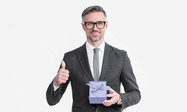 mature man in eyeglasses and suit hold present box isolated on white background. thumb up. - Foto, imagen
