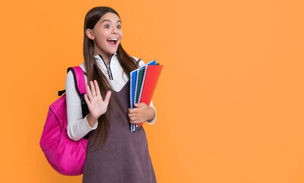 amazed child with school backpack and workbook on yellow background. - Foto, imagen