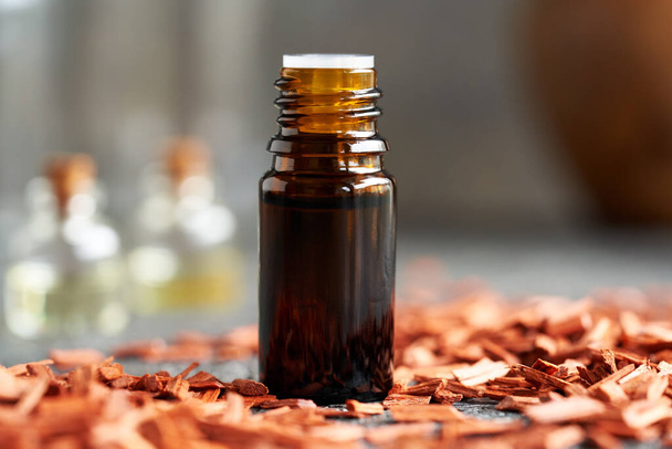 Botella de aceite esencial con virutas de sándalo rojo en una mesa - Foto, Imagen