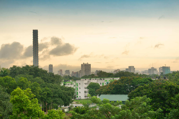 Kolkata, Nyugat-Bengál, India - 06.08.19: Kalkutta történelmi városának látképe. Zöld fák az előtérben, amelyek Kalkutta épületeit és városképét fedik le a reggeli égbolt alatt a horizonton. Kolkata város fényképe. - Fotó, kép