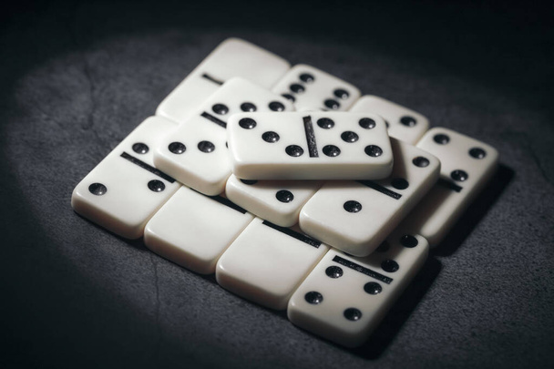 eenvoudige klassieke domino tegels in het wit op een donkere achtergrond, zwart-wit foto - Foto, afbeelding