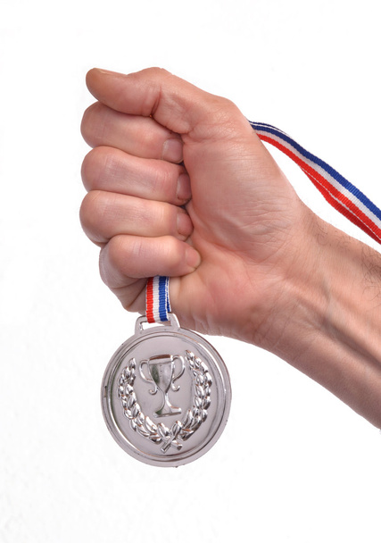 Mão segurando uma medalha de prata
 - Foto, Imagem