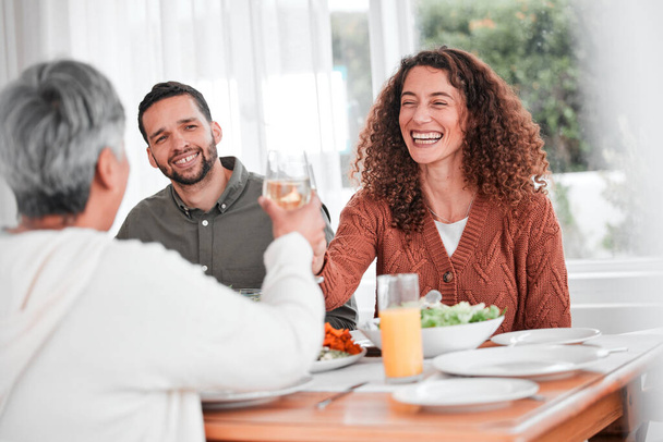 Cena familiar, pareja y vítores de una mujer feliz con comida sana en un hogar. Celebración, juntos y personas con unidad de comer en la mesa con felicidad y una sonrisa en una casa con brindis. - Foto, Imagen
