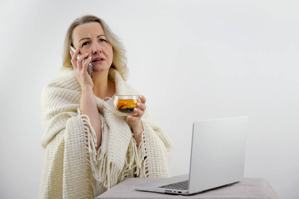 Ver sobre los hombros de una pareja enferma en mantas usando una computadora portátil para una conferencia en línea con su médico. mujer con fiebre son calentados por el té y tienen temperatura - Foto, imagen
