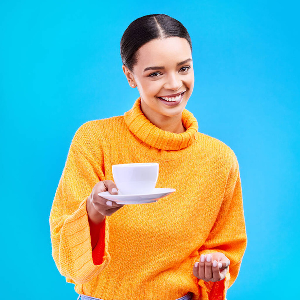 Mujer, retrato y sonrisa con café en estudio para la felicidad de la publicidad café y maqueta. Cara de una modelo femenina feliz dando taza de té sobre un fondo azul en la mano para la motivación y la hospitalidad. - Foto, Imagen