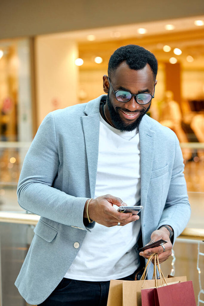 man checks Bank Account After Successful Shopping In Mall. close up photo. guy texting, sending message, sms to his girlfriend.guy with amazed shocked expression holding packagessmartphone - Foto, Imagem