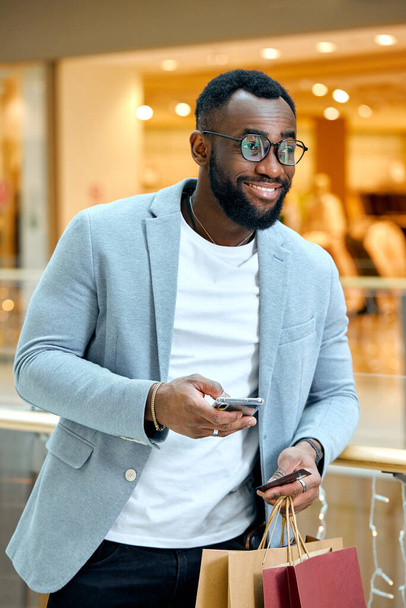 joyful good-looking smart man in fashion clothes doing online shopping, close up side view photo - Foto, Bild