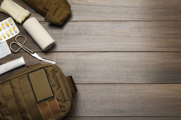 Military first aid kit on wooden table, flat lay. Space for text - Fotoğraf, Görsel