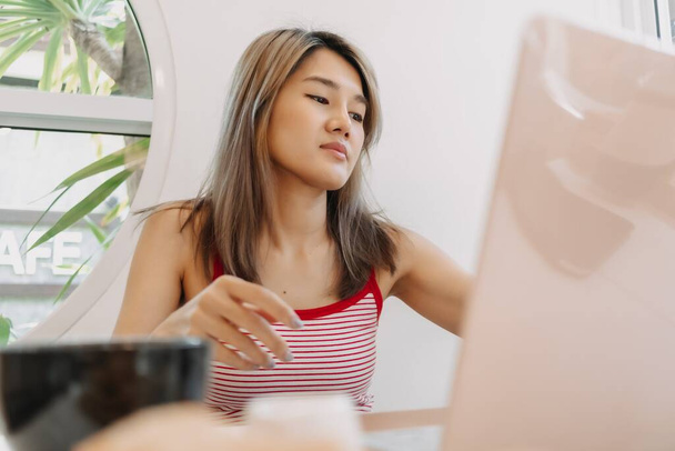 Freelance asian girl working digital online on laptop in the cafe. - Zdjęcie, obraz