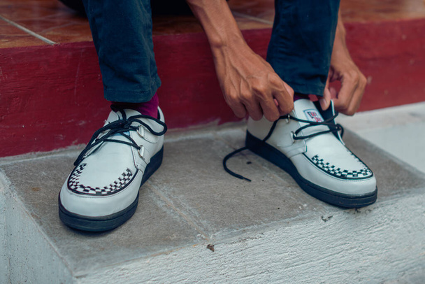 De cerca de estas zapatillas blancas de creepers hechas de cuero genuino con suelas negras que los hombres usan para sentarse. Estos zapatos casuales pero elegantes son hechos a mano por artesanos de zapatos caseros. - Foto, imagen