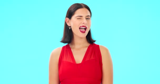 Happy, woman and winking face on blue background, studio and color backdrop. Portrait, female model and smile for wink, secret and fun mood in red dress, personality and happiness for flirting emoji. - Footage, Video