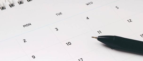 予定会議やスケジュール管理のためのカレンダーの月のスケジュールは、毎日のレイアウトや仕事や旅行の概念を計画するための木製の背景にペン。バナーコピースペース. - 写真・画像