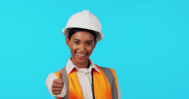Happy woman, architect and thumbs up in studio for success or good job in construction against a blue background. Portrait of female engineer smile showing thumb emoji, yes sign or like on mockup. - Footage, Video