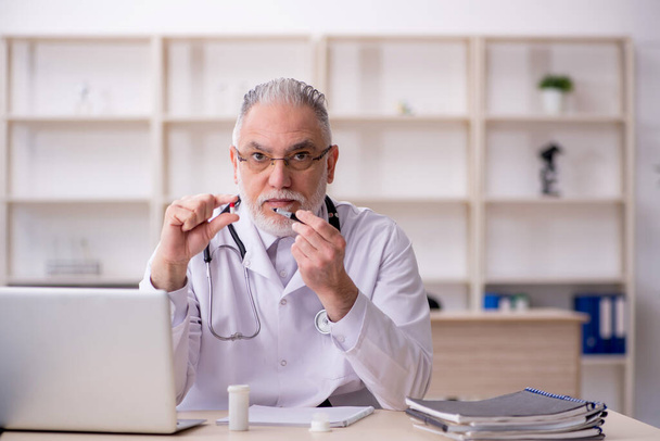 Vieux médecin masculin suggérant des pilules à l'hôpital - Photo, image