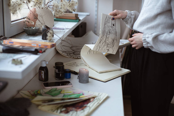 vrouwelijke kunstenaar kijken naar haar werk tekening met pen en zwarte inkt. Grafisch schilderen. Moderne kunst creëren - Foto, afbeelding