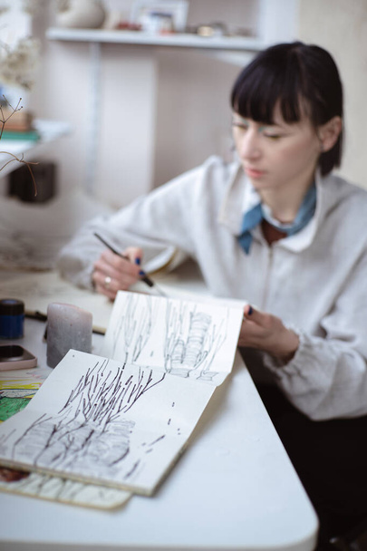 ペンと黒インクで絵を描く女性アーティスト。グラフィック絵画。現代美術の創造 - 写真・画像