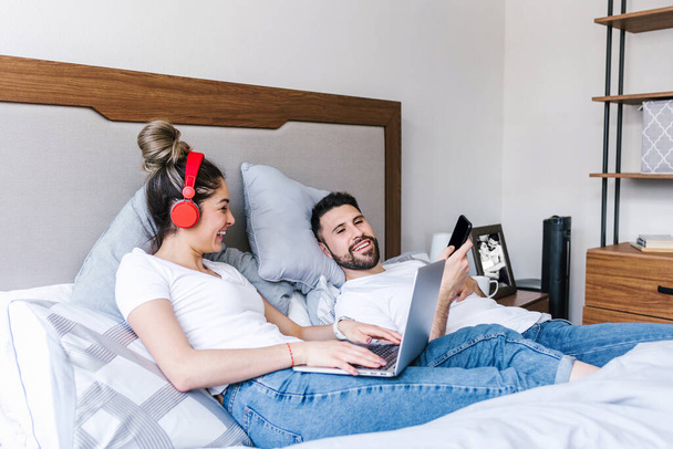 latin couple in bed using laptop or computer at home in Mexico, hispanic people - 写真・画像