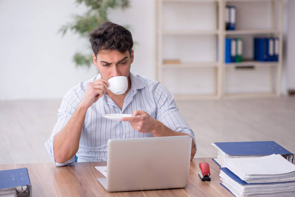 Young employee drinking coffee during breakfast - Photo, Image