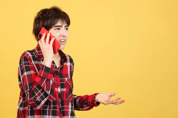 Mérges androgén személy beszél a mobil stúdióban sárga háttér - Fotó, kép